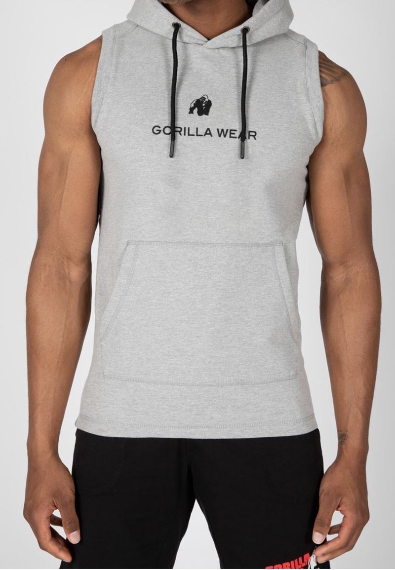 Hoodie sans manches gris avec une poche avant et des cordons noirs, arborant un logo imprimé en noir sur la poitrine. Matière en mélange de coton.