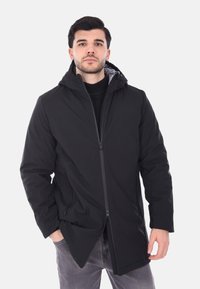 Giacca nera con cappuccio, chiusura frontale con zip, due tasche laterali, fodera testurizzata e design snello. Materiale leggero e resistente alle intemperie.