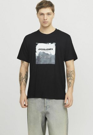 Sort bomulds T-shirt med et rektangulært grafisk print med "JACK&JONES" tekst og grå nuancer. Løs pasform, korte ærmer.