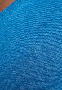 Blauer Baumwollpullover mit strukturiertem Strickmuster, rundem Ausschnitt und dezent eingeprägtem Logo im Stoff.