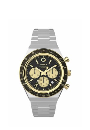 Timex quartz chronograph watch with black dial, gold accents, three subdials, tachymeter scale, date window, and silver metal link band.
