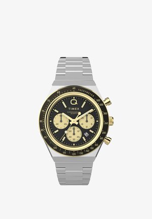 Timex quartz chronograaf horloge met zwarte wijzerplaat, gouden accenten, drie subdials, tachymeterschal, datumaanduiding en zilverkleurige metalen schakelband.