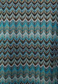 Dzianina w splot w kształcie chevron w odcieniach turkusu, czerni, brązu i kremu. Teksturowany wzór charakteryzuje się ażurowymi elementami oraz różnorodnymi rozmiarami ściegów.
