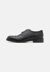Chaussure de ville noire en cuir avec bout arrondi, texture lisse, design à lacets à cinq œillets et détails de couture subtils sur les côtés.