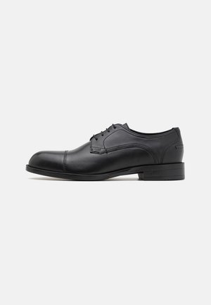 Chaussure de ville noire en cuir avec bout arrondi, texture lisse, design à lacets à cinq œillets et détails de couture subtils sur les côtés.