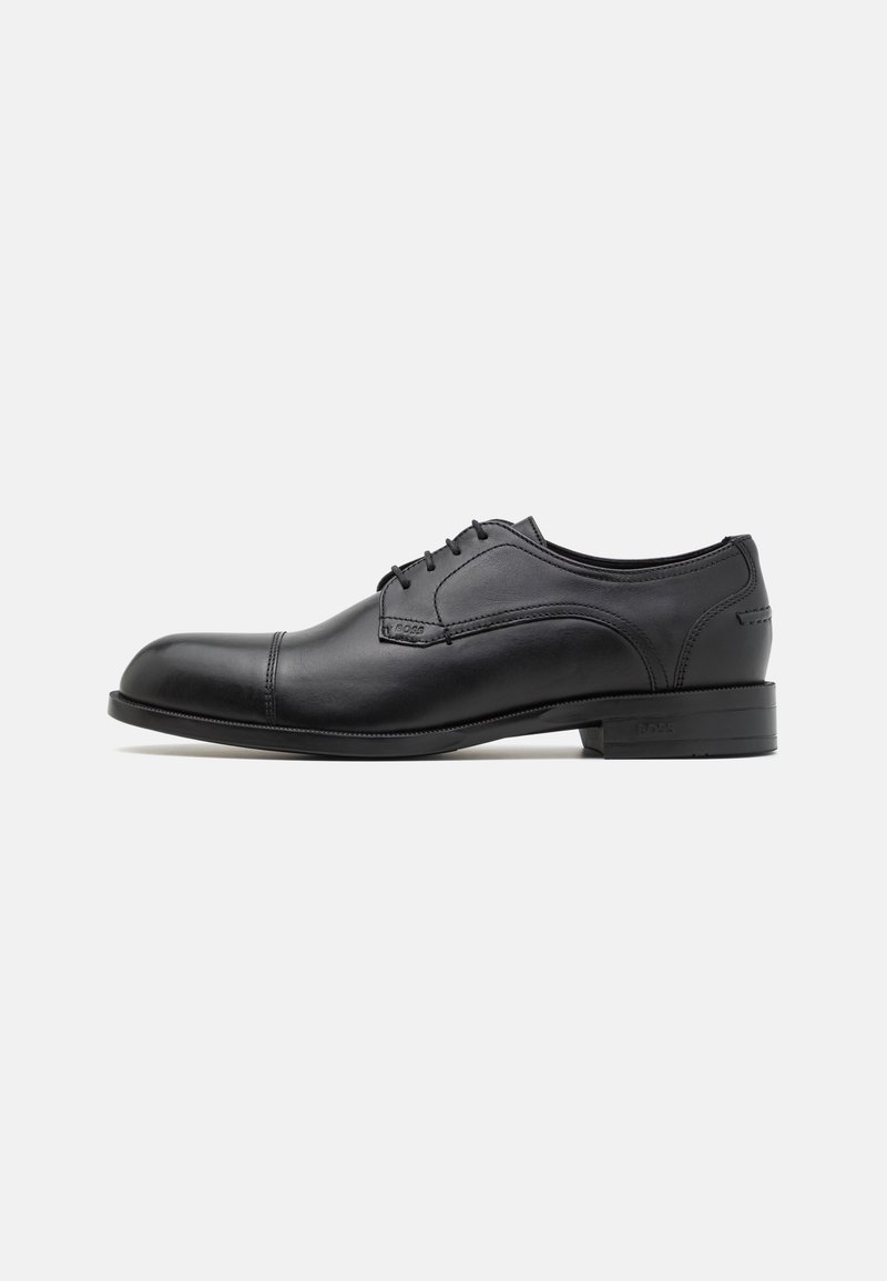 Chaussure de ville noire en cuir avec bout arrondi, texture lisse, design à lacets à cinq œillets et détails de couture subtils sur les côtés.