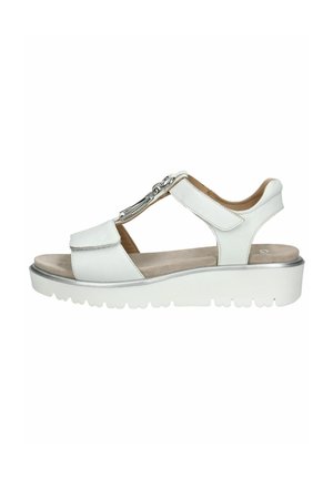 Sandale en cuir blanc avec un design à lanière en T, des accents argentés, une semelle intérieure rembourrée et une épaisse semelle en caoutchouc blanc avec un motif texturé.