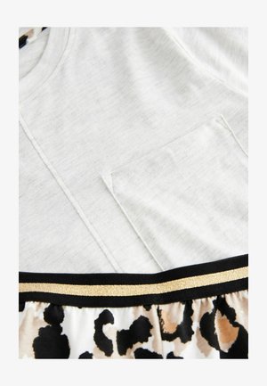 Lys grå top med en brystlomme, parret med en nederdel i leopardmønster med en sort talje og guld accenter. Blød bomuldsstruktur.