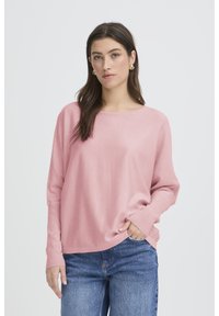 Pull rose clair en maille avec un col rond et des manches longues, doté de poignets côtelés et d'une coupe décontractée. Associé à un jean en denim.