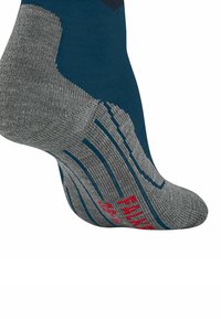Calzino grigio e teal con tallone e punta rinforzati, caratterizzato da un motivo testurizzato sulla suola e un marchio rosso. I materiali sembrano morbidi e durevoli.