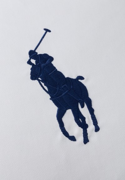 Σκούρος μπλε κεντημένος παίκτης πόλο πάνω σε άλογο που κρατάει μαλέτα, σε λευκό φόντο υφάσματος.