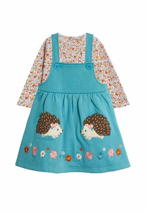 Morska bawełniana sukienka na ramiączkach, ozdobiona aplikacjami jeży i kwiatowym haftem na dole, noszona na kwiatowej bluzce z długim rękawem.