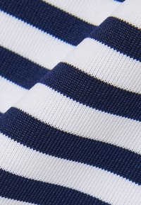 Gros plan sur un tissu texturé à rayures horizontales bleu marine et blanches montrant le motif tricoté et les plis.