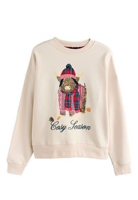 Sudadera color crema con un gráfico de una vaca de las Highlands con un sombrero y bufanda a rayas, con el texto "Cosy Season" debajo.