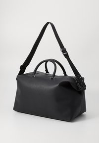 Sac de voyage en cuir noir avec deux poignées, bandoulière réglable, texture lisse, design minimaliste et accents en métal argenté.