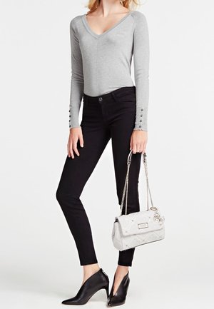 Šedý dlouhý rukáv bodysuit s výstřihem do V, černé přiléhavé kalhoty a černé lodičky s špičatou špičkou; drží bílou prošívanou kabelku se stříbrným řetízkem.
