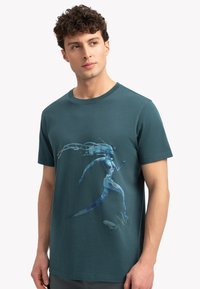 Teal katoenen T-shirt met ronde hals, featuring een kleurrijk grafisch ontwerp van een rennende figuur. Korte mouwen en een comfortabele pasvorm.