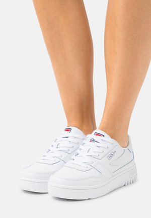 Sneaker bianche con tomaia in pelle liscia, punta rotonda, suola testurizzata e logo Fila sulla linguetta e sul lato. Design delle lacci semplice.