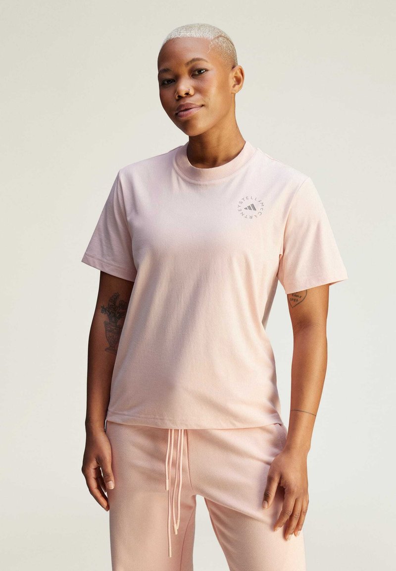 Light pink cotton t-shirt with short sleeves, round neckline, and a small logo print on the left chest, paired with matching light pink pants.