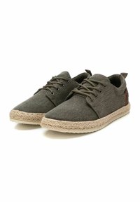 Zapatos verdes de lona con cordones y acabado texturizado, que presentan una suela de yute trenzado y detalles en cuero marrón.