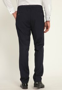 Pantaloni della marina in stretto con vita elasticizzata, tasche posteriori e gamba affusolata. Tessuto leggero che offre una texture liscia e una vestibilità aderente.