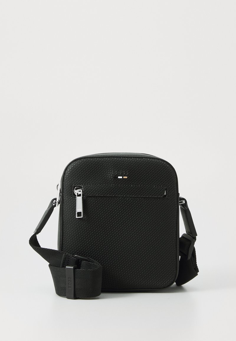 Borsa a tracolla nera realizzata in materiale testurizzato. Presenta un compartimento principale con cerniera, una tasca frontale e una tracolla regolabile. Design minimalista.