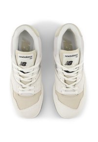 Le sneakers New Balance 550 bianche e crema presentano una tomaia testurizzata con materiali in mesh e pelle, punta rotonda e un classico design con lacci.