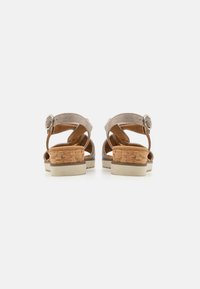 Beige suède sandalen met kurken hak, voorzien van kruisbanden en een metalen gesp. Platformzool met een stevige grip voor stabiliteit.