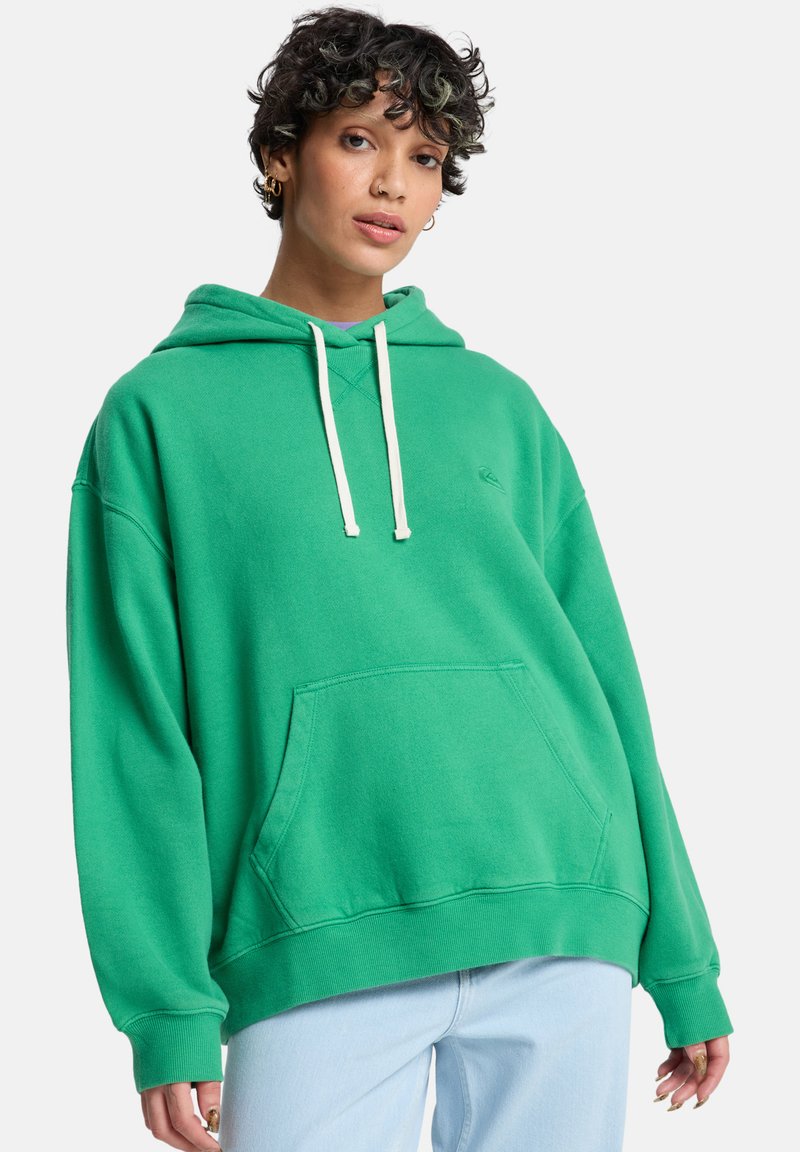 Grüner übergroßer Kapuzenpullover aus weichem Stoff, mit einer Fronttasche, verstellbarer Kapuze und gerippten Bündchen. Einfaches Design mit minimalen Details.