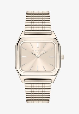 Montre carrée dorée avec un cadran beige brossé, des index horaires argentés et un bracelet en maille texturée. Présente une couronne sur le côté.