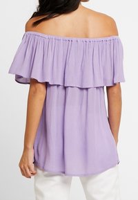 Lilafarbenes Top mit schulterfreiem Design, mit Rüschendetails, leichtem Stoff und lockerer Passform; verfügt über einen elastischen Ausschnitt und eine fließende Silhouette.
