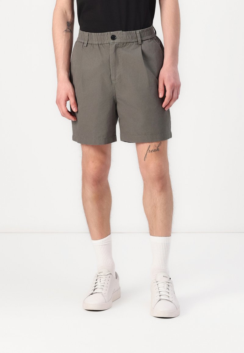 Pantaloni corti grigi con vita elasticizzata e bottone frontale. Il tessuto sembra leggero e morbido, con tasche laterali.