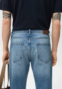 Lichtblauwe denim jeans met een rechte pasvorm, voorzien van twee achterzakken, subtiele vervaging en een bruine leren patch op de tailleband.