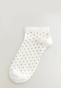 Valge pazuka socks, millel on sooniline tekstuur ja väikesed, ühtlaselt paigutatud heledat pruunid täpid. Varbaosa on ümar.