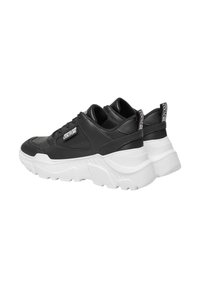 Baskets en cuir noir épais avec une semelle blanche et des accents texturés. Présente une étiquette logo sur le talon et des détails perforés sur les côtés.