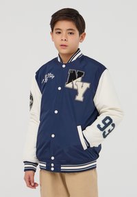 Granatowa i biała kurtka varsity z haftowanym napisem "NY" oraz "93", z zatrzaskami, paskowanymi mankietami oraz kieszenią z przodu.