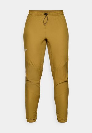 Pantaloni leggeri di colore senape, realizzati in tessuto sintetico, con elastico in vita e cordoncino, e gambe affusolate con dettagli a pannello.