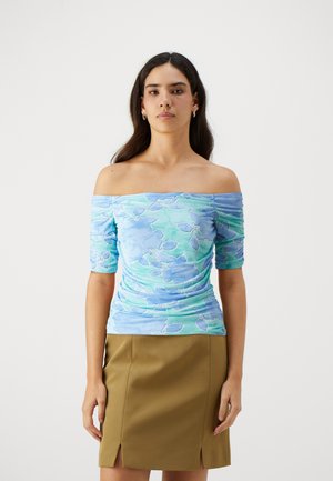 Blue off-the-shoulder top with floral pattern, short sleeves, and ruching detail, paired with a fitted olive-green skirt with slits.