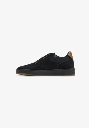 Low-top black suede sneaker with black laces, brown heel tab, and gum rubber sole shown in side profile on white background.