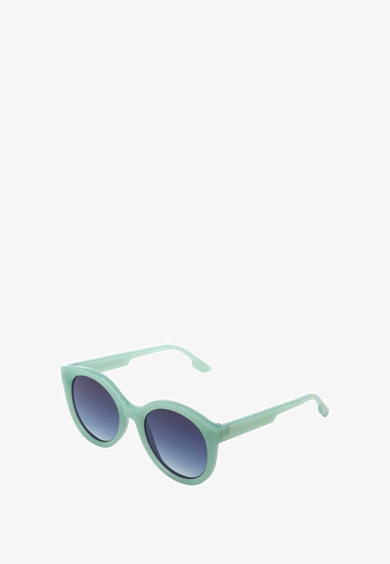 Lunettes de soleil rondes avec des montures translucides vert menthe et des verres sombres dégradés, inclinées sur un fond blanc.