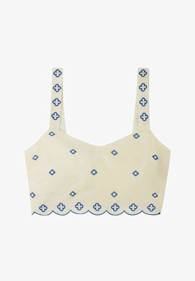 Haut court beige clair avec des motifs géométriques bleus, ourlet festonné et fines bretelles avec des détails assortis le long des bords.