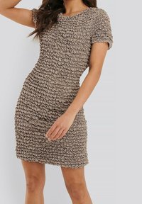 Beige jurk met korte mouwen van textuur, gegatherde stof. Strak silhouet met een ronde halslijn, knielange zoom en een zachte glans.