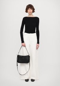 Top nero a maniche lunghe, pantaloni bianchi a gamba larga e una piccola borsa nera testurizzata con tracolla. Tessuto liscio e dettagli di design eleganti.