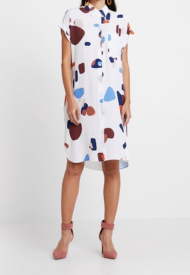 Robe à manches courtes blanche boutonnée, ornée de formes abstraites multicolores en bleu, marron et orange. Tissu lisse avec une coupe décontractée.