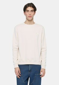 Felpa color beige chiaro in cotone con scollo rotondo, polsini e orlo a costine, con un piccolo logo ricamato sul petto.