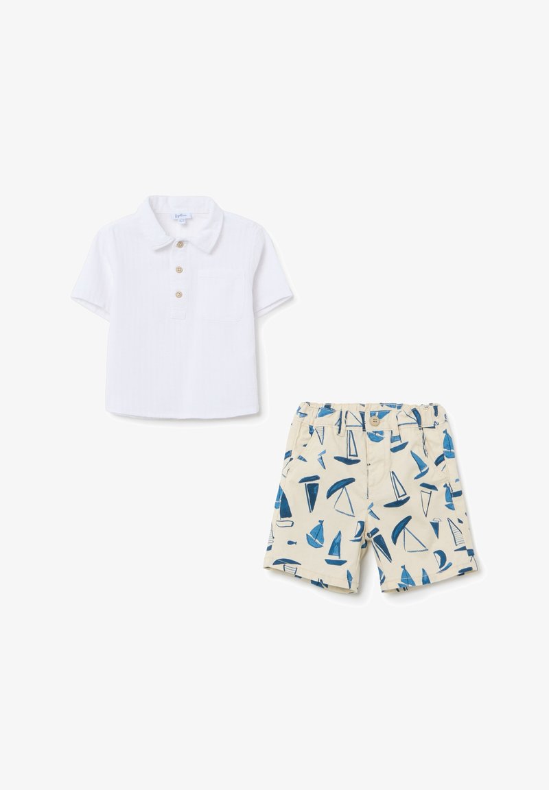 Polo shirt blanc à manches courtes avec trois boutons et une poche, associé à un short beige avec un motif de voilier bleu.
