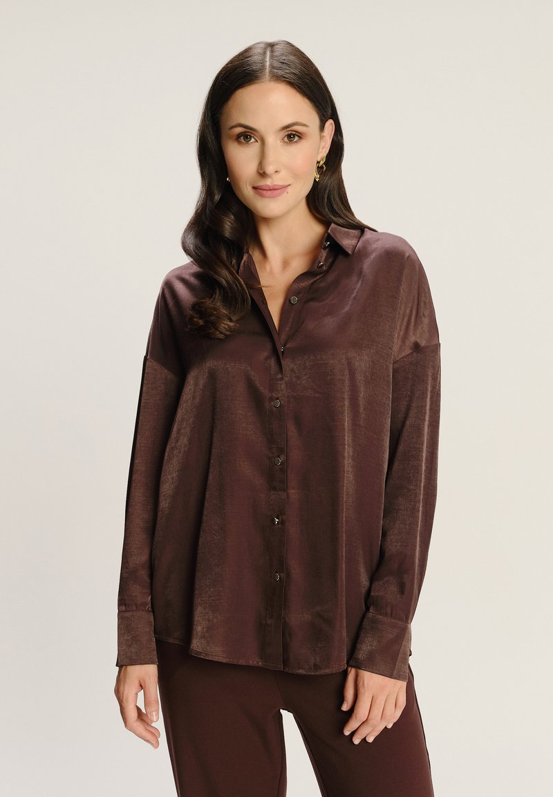 Camisa marrón de botones hecha de un material seda con un brillo sutil, que presenta mangas largas, un cuello y un corte relajado.
