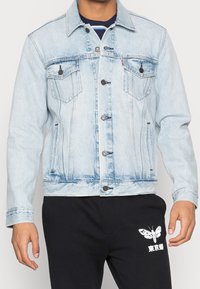 Valkobrädi denimtakki, jossa on kaksi rintataskua, nappikiinnitys ja napitettu hihansuu. Ominaisuuksiin kuuluu hieman haalistunut pesu ja kontrastivärinen ompelu.