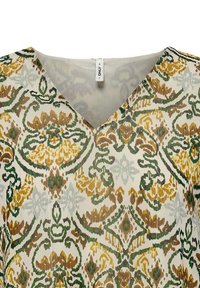 Blouse à col en V avec un motif floral et cachemire en vert, jaune et marron sur un fond clair ; tissu léger avec une texture délicate.