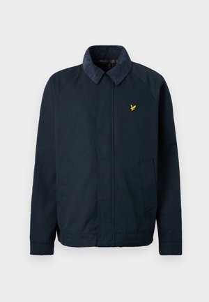 Veste bleu marine avec un col doux et texturé, dotée de deux poches latérales et d'un petit logo doré en forme d'oiseau sur la poitrine.